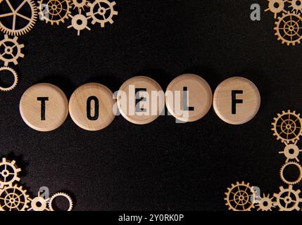 Holzblöcke mit der Aufschrift „TOEFL“ symbolisieren Bildungseinschränkungen. Stockfoto