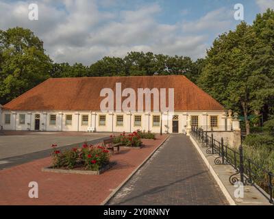 Innenhof mit historischem Gebäude, rotem Dach und umgeben von Bäumen mit Blumenbeet, dornum, ostfriesland, deutschland Stockfoto