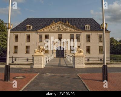 Elegantes historisches Herrenhaus mit Löwenstatuen und Fahnenmasten vor blauem Himmel, dornum, ostfriesland, deutschland Stockfoto