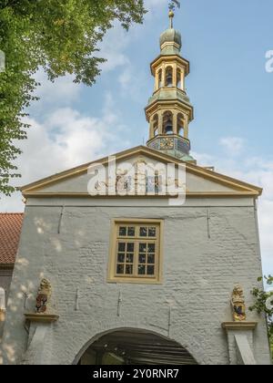 Weiße Fassade mit Glockenturm und bunten Wappen darauf, Fenster und blauer Himmel im Hintergrund, dornum, ostfriesland, deutschland Stockfoto