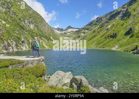 Wanderer mit Blick auf die Dorfer See im Hintergrund die Kalser Tauern, Bergsee, blauer Himmel, Dorfertal, Nationalpark hohe Tauern, Kals am Grossglock Stockfoto