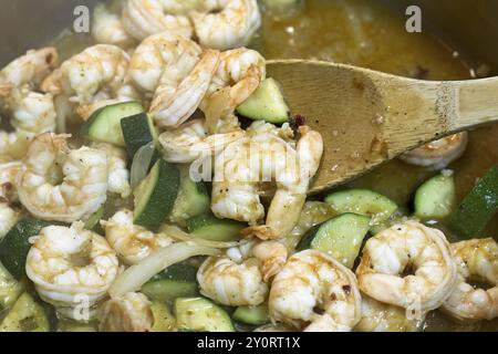 Nahaufnahme eines Garnelenbruchs, einschließlich Zucchini, Zwiebeln, Öl und Gewürzen, in einer Pfanne gekocht Stockfoto