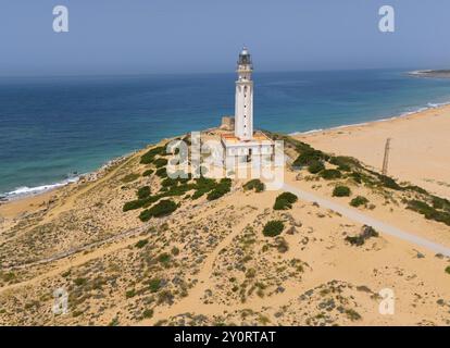 Leuchtturm an einer Küste mit Blick auf das weite Meer und den Strand unter klarem Himmel, aus der Vogelperspektive, Faro de Trafalgar, Cape Trafalgar, Provinz Cadiz, Stockfoto