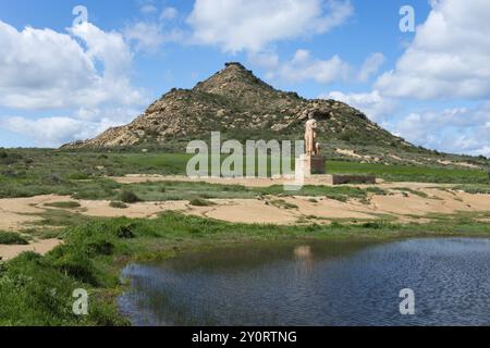 Eine Statue steht vor einem grasbewachsenen Hügel und einem Teich unter einem bewölkten Himmel, Monument, Pastor Bardenero, Bardenero Hirte, Bardenas Reales Naturpark, Stockfoto