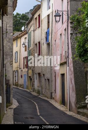 Enge Gasse mit alten Gebäuden und pastellfarbenen Wänden, Laternen und mediterranem Charme in der historischen Stadt Vauvenargues, Provence-Alpes-Cote d'Azur Stockfoto