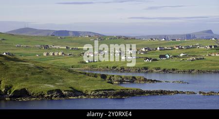 Ein ländliches Dorf mit kleinen Häusern, umgeben von grünen Hügeln und Feldern an einer Küste, Festland, Shetland-Inseln, Schottland, Vereinigtes Königreich, Europa Stockfoto