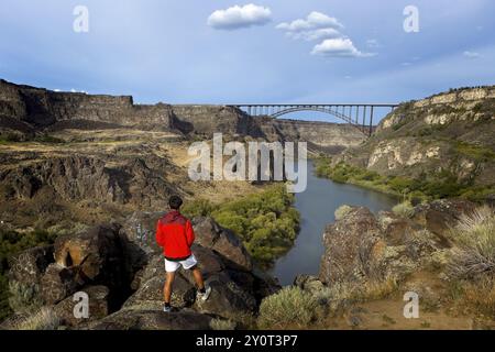 Ein Teenager steht auf einem Felsvorsprung mit Blick auf den majestätischen Snake River und die Perrine Bridge in Twin Falls, Idaho Stockfoto