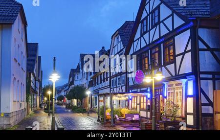 Muenchhausen Stadt Bodenwerder bei Nacht. Große Straße in der historischen Altstadt mit Fachwerkhäusern und Kopfsteinpflaster. Bodenwerder, Weserbergla Stockfoto