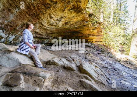 Eine Wanderer ruht sich in einer kleinen Grotte in der Red River Gorge in Kentucky aus Stockfoto