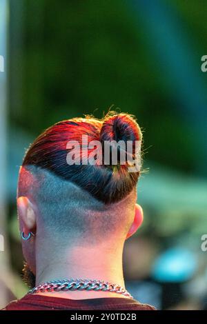 Stage Spotlight: Nahaufnahme von Young man's Single Bun Hairstyle – Partial Shave, Night Time Performer. Stockfoto
