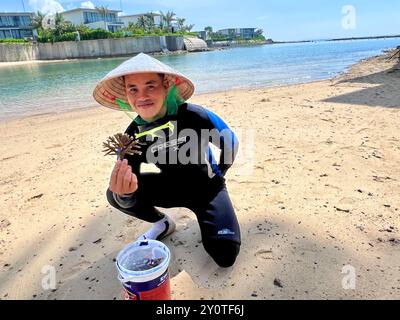 Nha Trang, Vietnam. August 2024. Ein Taucher, der für das gemeinsame Korallenprojekt des Hotels Villa Le Corail und der Firma Avatar arbeitet, hält am Strand von Nha Trang eine Koralle vom Typ Acropora muricata (kleine Polypen Steinkoralle). Vermerk: Carola Frentzen/dpa/Alamy Live News Stockfoto