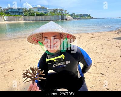 Nha Trang, Vietnam. August 2024. Ein Taucher, der für das gemeinsame Korallenprojekt des Hotels Villa Le Corail und der Firma Avatar arbeitet, hält am Strand von Nha Trang eine Koralle vom Typ Acropora muricata (kleine Polypen Steinkoralle). Vermerk: Carola Frentzen/dpa/Alamy Live News Stockfoto