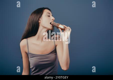 Eine junge Frau genießt eine Eisbar, die Augen sind geschlossen und lächelt glücklich. Perfekter Sommer-Snack für eine erfrischende Pause von gesunder Ernährung Stockfoto