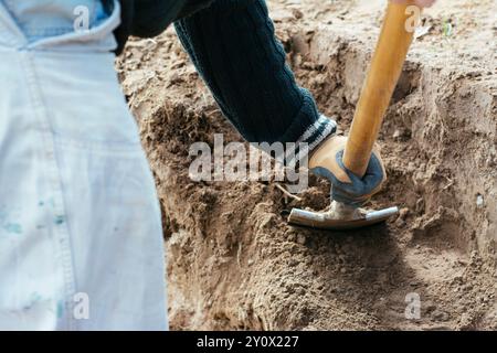 Ein Mann, der eine Pflanzenterrasse eines Teichs ausgräbt. Stockfoto