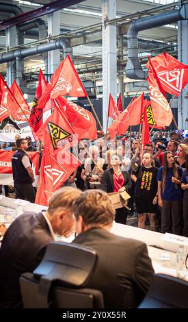 Wolfsburg, Deutschland. September 2024. Mitarbeiter protestieren vor Beginn einer Betriebsbesprechung in einer Halle des VW-Werks. Volkswagen hat angekündigt, seine Sparmaßnahmen aufgrund der angespannten Lage der Kernmarke zu verschärfen. Selbst obligatorische Entlassungen und Werksschließungen konnten nicht mehr ausgeschlossen werden. Kredit: Moritz Frankenberg/dpa Pool/dpa/Alamy Live News Stockfoto