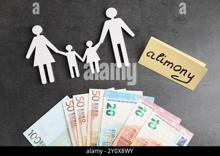 Karte mit Wort Alimente, Euro-Banknoten und Familienfiguren auf grauem Tisch, flach gelegt Stockfoto