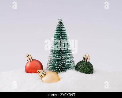 Weihnachtsszene mit grünem Weihnachtsbaum und bunten Weihnachtskugeln auf Schnee vor weißem Hintergrund. Minimales Weihnachts- und Neujahrskonzept. Stockfoto