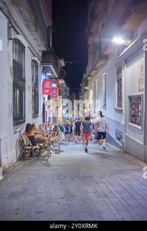 Sitges, Barcelona - 04. September 2024: Ruhiger Moment zwischen weißen Gebäuden mit traditionellen Details unter dunklem Himmel. Stockfoto