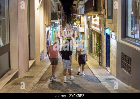 Sitges, Barcelona-04. September 2024: Gemütliche Gasse mit warmer Beleuchtung lädt zu einem Spaziergang in einer ruhigen mediterranen Nacht ein. Stockfoto