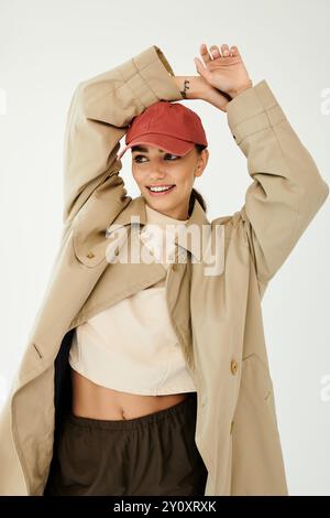 Eine schöne junge Frau präsentiert ihr trendiges Herbstoutfit und strahlt Freude in einer eleganten Studioumgebung aus. Stockfoto