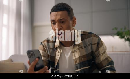 Wütender afroamerikanischer Mann birassisch verrückter männlicher ethnischer Kerl Benutzer wütend genervt irritiertes Sprechen Schreien Schreien Handy Videoanruf Chat Stockfoto