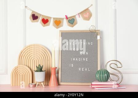 Brieftafel mit Phrase alles, was Sie sich vorstellen können, ist echt und Dekorationselemente auf rosa Holztisch Stockfoto