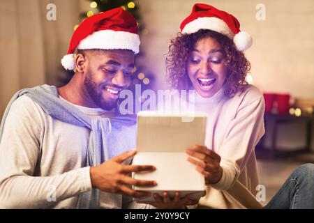 Überglücklich afro Paar öffnen xmas Box und innen suchen Stockfoto