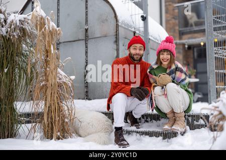 Ein junges Paar sitzt im Winter auf der Veranda ihres Hauses Stockfoto