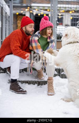 Ein junges Paar mit Hund auf der Veranda ihres Hauses im Winter Stockfoto