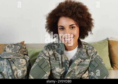 Eine junge Frau in Militärkleidung lächelt hell, bereit, sich auf ihre Dienstreise zu begeben. Stockfoto