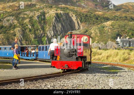 Tourist attraction: Fairbourne Steam Railway, Gwynedd, Wales, UK. Front view of red locomotive, passengers waiting for departure on a sunny, summer day. Stockfoto
