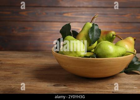 Frische grüne Birnen und Blätter in der Schüssel auf Holztisch. Leerzeichen für Text Stockfoto