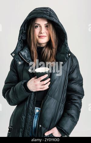 Porträt einer Frau mit Kapuzenmantel, die eine Tasse Kaffee hält Stockfoto
