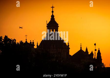 Ein Flugzeug startet vom Flughafen Sevilla, wenn die Dämmerung über den Dächern der südspanischen Stadt bricht. Stockfoto