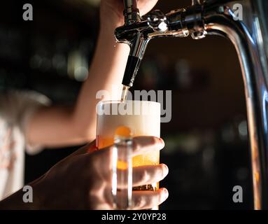 Bier an einem Zapfhahn in einem Pub gießen. Goldenes Bier mit Bläschen Stockfoto