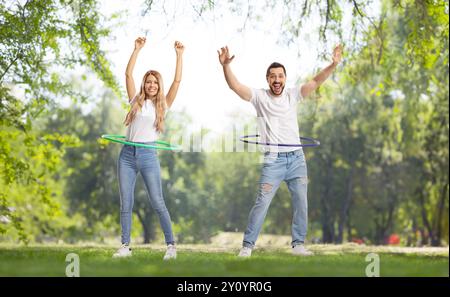 Porträt eines jungen Mannes und einer Frau, die in einem Park Hula Hoop spinnen Stockfoto