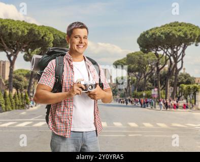 Männlicher Tourist mit einem Rucksack, der eine Kamera in Rom hält Stockfoto