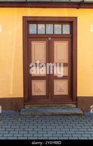 Die Tür hat ein sattes braunes Finish mit einzigartigen Mustern und steht auf einer Steintreppe. Stockfoto