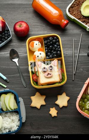 Lunchboxen mit verschiedenen Snacks, eine Flasche Saft und Besteck auf Holztisch, flache Ladefläche Stockfoto