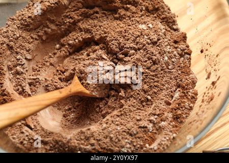 Schokoladenteig herstellen. Mischung aus Kakaopulver mit Mehl und Löffel in der Schüssel auf dem Tisch, Draufsicht Stockfoto