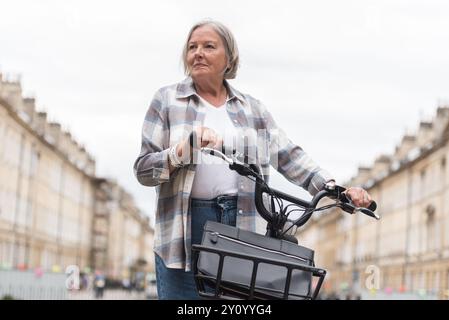 Eine ältere Frau auf einem Elektrofahrrad hält an Stockfoto