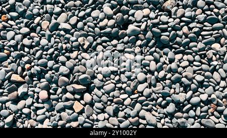 Kieselsteine am Strand aus der Nähe von oben, Textur, graue Farbe, Hintergrund Stockfoto
