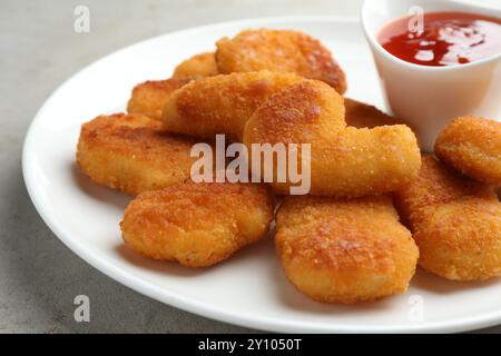 Leckere Chicken Nuggets mit Chili-Sauce auf grauem Tisch, Nahaufnahme Stockfoto