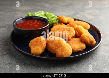 Leckere Chicken Nuggets mit Chili-Sauce auf grauem Tisch Stockfoto