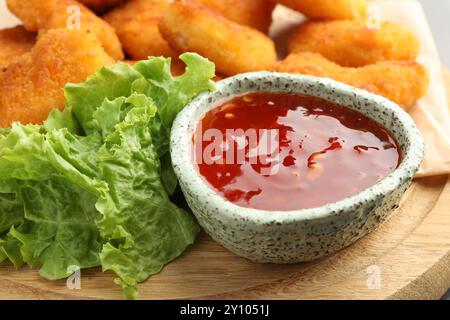 Heiße Chili-Sauce, Salat und Nuggets auf Holzbrett, Nahaufnahme Stockfoto