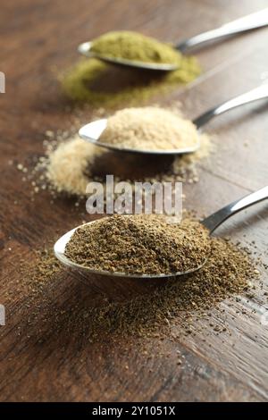 Verschiedene Superfood-Pulver in Löffeln auf Holztisch, Nahaufnahme Stockfoto