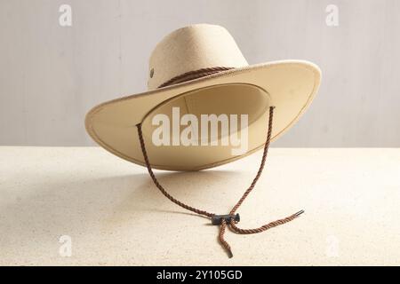 Nahaufnahme eines Mannes Cowboyhut mit Kinnriemen, der Hut fliegt über einem Tisch und weißem Hintergrund Stockfoto