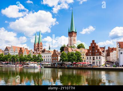 Flussufer des historischen Zentrums von Lübeck, mit Blick auf die Kirchtürme St. Peter (rechts) und St. Marienkirchen (links). Stockfoto