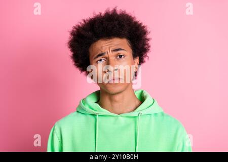 Porträt des netten jungen Mannes mürrisch trauriges Gesicht tragen grünen Hoodie isoliert auf rosa Hintergrund Stockfoto