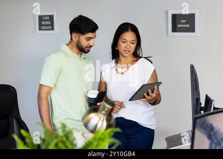Diskutieren Sie das Projekt, verwenden Sie ein Tablet und halten Sie eine Kaffeetasse in einem modernen Büro Stockfoto